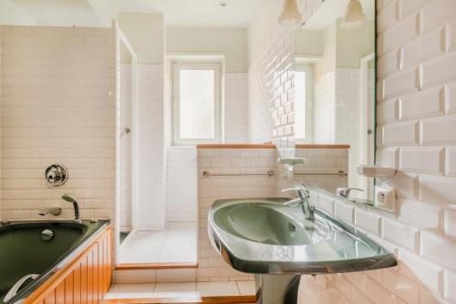 La salle de bains est pourvue d'un lavabo vert et d'une baignoire. dans l'établissement Saint-Germain Prestige Residence, à Paris