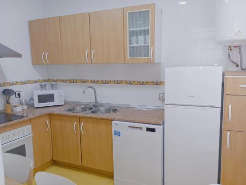 eine Küche mit weißen Geräten und Holzschränken in der Unterkunft VACATIONAL HOMES South Organic in Málaga