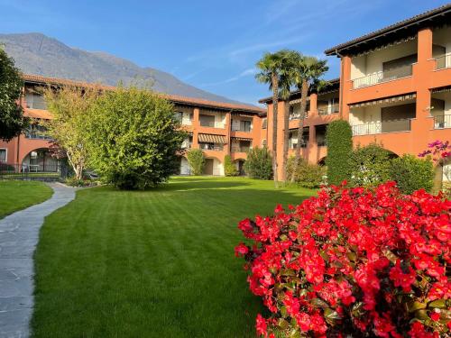 um prédio de apartamentos com flores vermelhas no quintal em Ascona: Sabrina Apt. 237 em Ascona