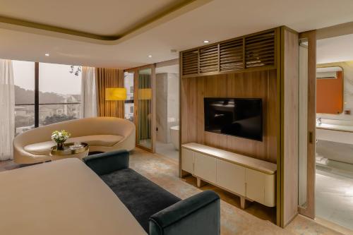a living room with a couch and a tv in a room at Hanoi Le Jardin Hotel & Spa in Hanoi