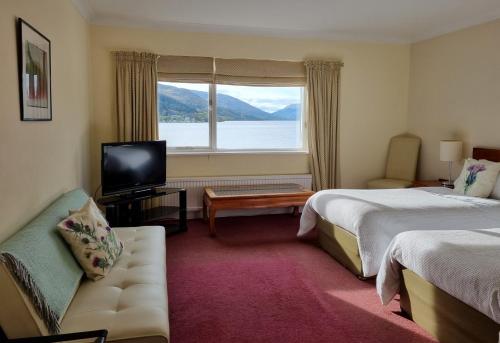 a hotel room with two beds and a television at The Four Seasons Hotel in Saint Fillans