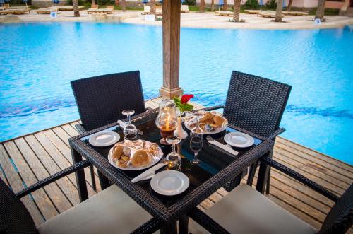 Eagles down town Zahabia &Beach Resort في الغردقة: طاولة مع أطباق من الطعام على طاولة بالقرب من مسبح