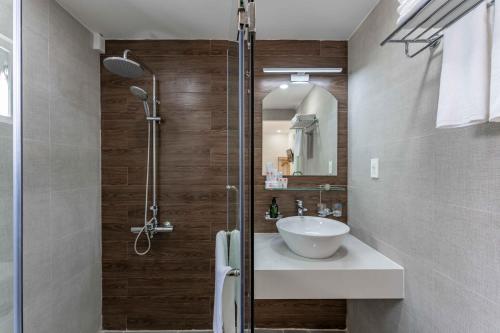 a bathroom with a sink and a glass shower at Edoya hotel Dong Khoi in Ho Chi Minh City