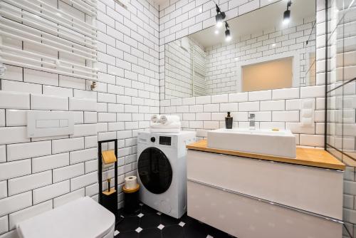 een witte badkamer met een wastafel en een wasmachine bij Apartament Lekka in Warschau