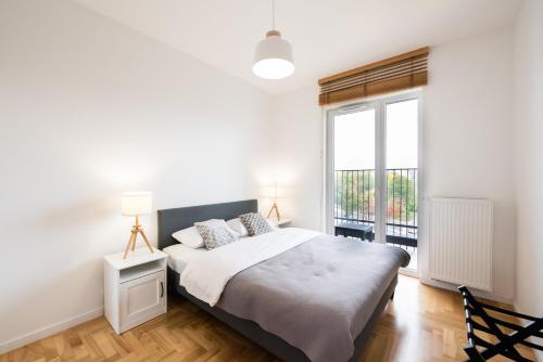 een slaapkamer met een bed en een groot raam bij Apartament Lekka in Warschau