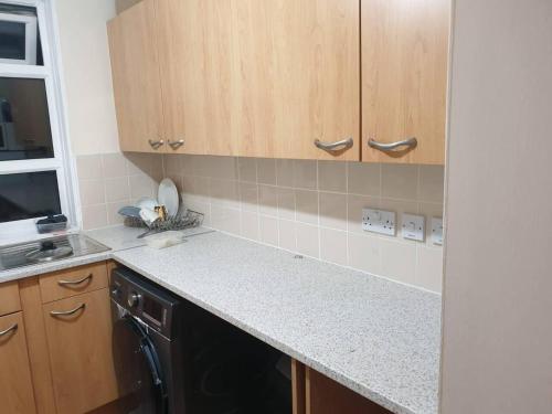 a kitchen with wooden cabinets and a black dishwasher at Your Home away from home in Leeds - on the Ring Rd in Leeds