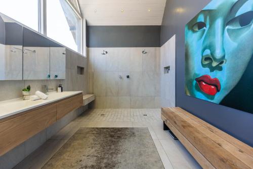a bathroom with a large painting of a woman at The Clarendon - Fresnaye in Cape Town