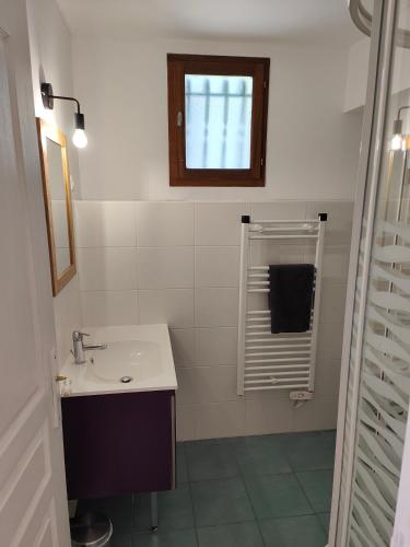 une salle de bain blanche avec un lavabo et une fenêtre dans l'établissement Appartement Boutx 4 PERSONNES, à Boutx