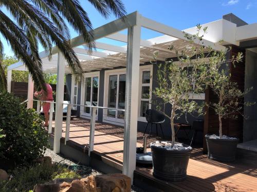 a pergola on a deck with trees on it at Bloemenzee Boutique B&B in Gordonʼs Bay