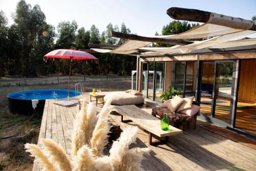 a house with a deck with a bench and an umbrella at Goodmuda Tipi's in Grândola