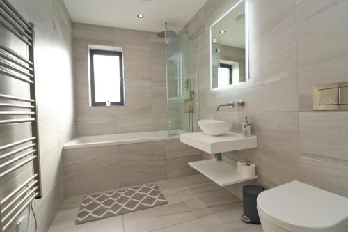 a bathroom with a sink and a toilet and a mirror at Stunning home, sea views, walk to beach in Saint Ervan