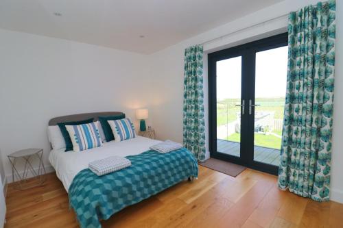 a bedroom with a bed and a sliding glass door at Stunning home, sea views, walk to beach in Saint Ervan