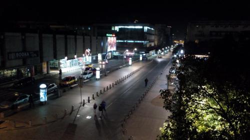 a city street at night with people walking down the street at Centre Point Apartment in Podgorica