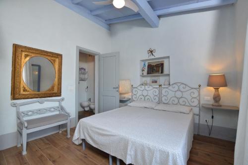 1 dormitorio con cama blanca y espejo en Villa Borgiano, en Scansano