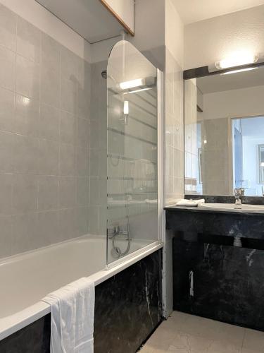 une salle de bain avec une douche, une baignoire et un lavabo dans l'établissement Appart'hôtel Le Trianon, à Arcachon