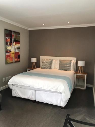 a bedroom with a large white bed with two lamps at Bloemenzee Boutique B&B in Gordonʼs Bay