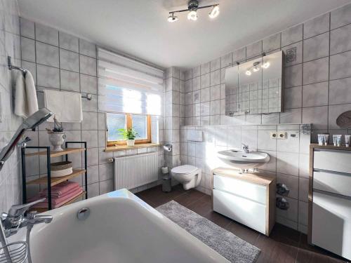 ein Badezimmer mit einer Badewanne, einem Waschbecken und einem WC in der Unterkunft Haus Andreas in Bodenmais