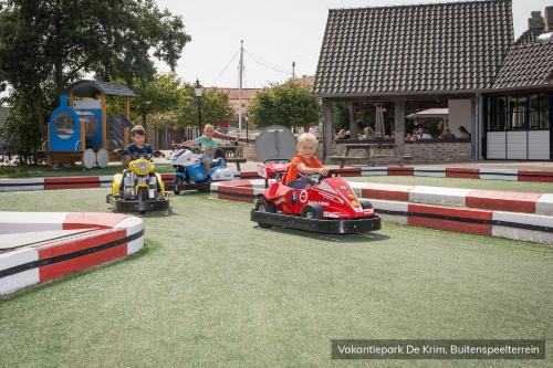 two children riding on toy cars in a playground at Vakantiepark De Krim Texel in De Cocksdorp