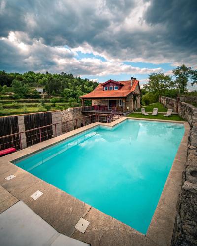 a large blue swimming pool in front of a house at Casa da Várzea - Serra da Estrela in Fornos de Algodres