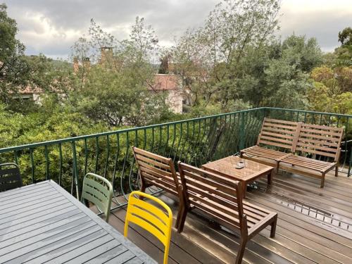 une terrasse avec deux bancs, une table et des chaises dans l'établissement Les cigales, au Lavandou
