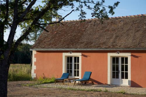 twee stoelen en een tafel voor een gebouw bij Domaine de la Trigalière in Ambillou