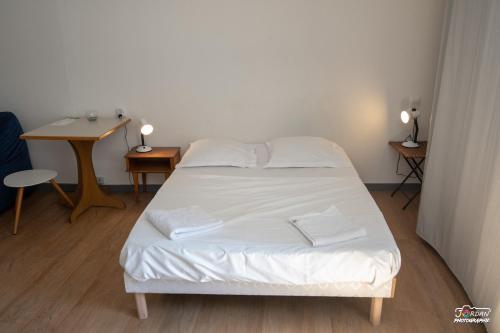 um quarto com uma cama com lençóis brancos e uma secretária em Hyper centre - wifi - cosy - Gare em Bourg-en-Bresse