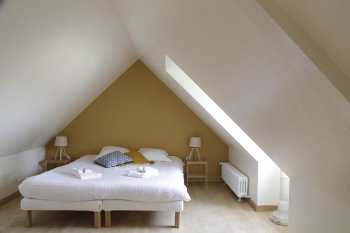 a bedroom with a white bed in a attic at Domaine de la Trigalière in Ambillou