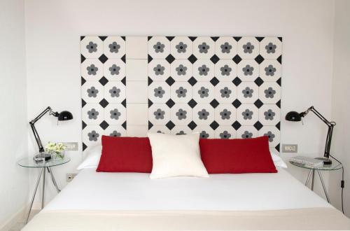 バルセロナにあるエリック ヴェケル ブティック アパートメント BCN スイーツのベッドルーム(白いベッド、赤い枕付)
