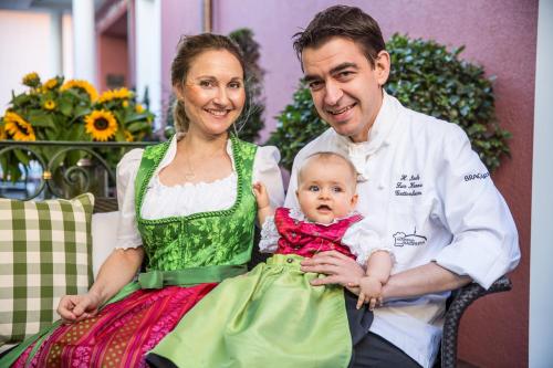 a man and a woman holding a baby in a green dress at Landhotel Restaurant zur Krone in Gottenheim