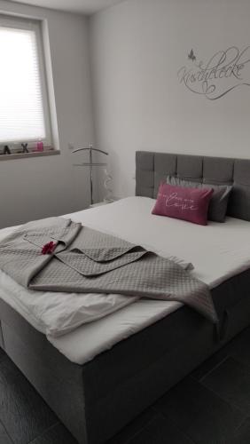 a bedroom with a large bed with a pink pillow at FeWo ALBTALECK - Wohnen im Kurort Waldbronn in Waldbronn