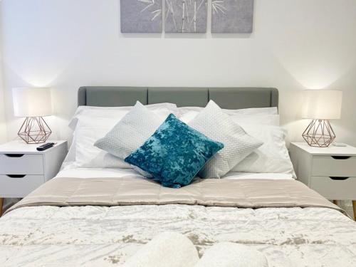1 cama con almohadas azules y 2 mesitas de noche en Gild House 2-bedroom apartment close to Town Centre en Bournemouth