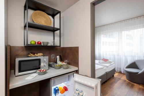 a small kitchen with a microwave and a small refrigerator at SORAT Hotel Berlin in Berlin