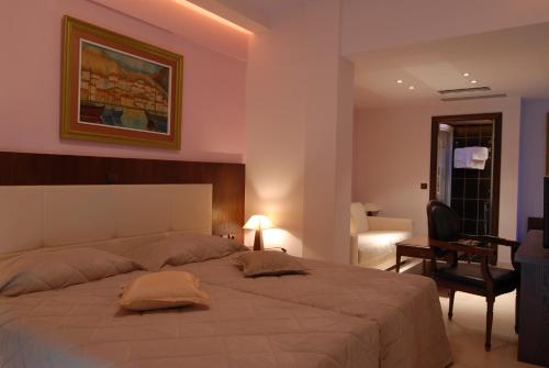 a bedroom with a large bed with a chair and a desk at Panorama Hotel in Paralia Katerinis