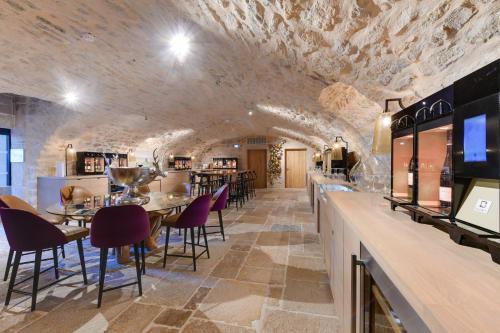 a restaurant with stone walls and tables and purple chairs at Hôtel & Spa Les Sept Fontaines Best Western Premier in Tournus