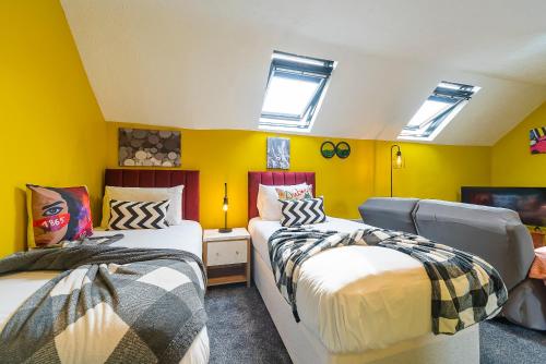 two beds in a room with yellow walls and windows at Jesouth Charming Superb Comfortable Pretty Studio Pad Wifi in Hull