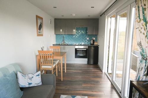 ein Wohnzimmer mit einem Sofa und einem Tisch sowie eine Küche in der Unterkunft Bluebell Cabin in Badsey
