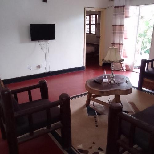 a living room with a table and chairs and a tv at Dream jet suites in Entebbe