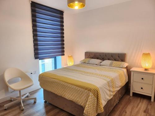 um quarto com uma cama, uma cadeira e uma janela em Lovely Luxury Apartment with Free Parking 801 em Luton