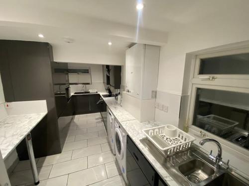 a white kitchen with a sink and a dishwasher at MBA COSY 4 bedroom house in Leavesden Green