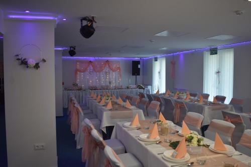 a banquet hall with white tables and chairs and purple lighting at Tisza-tó Apartmanpark in Kisköre