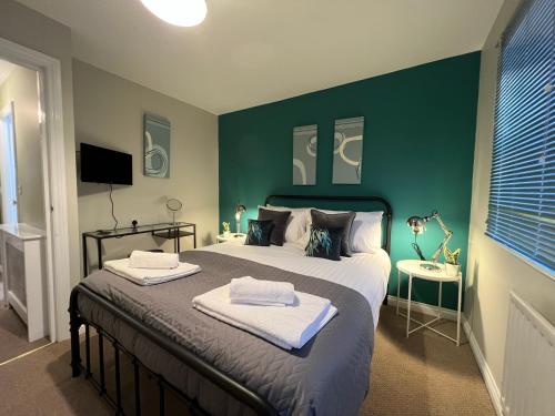 een slaapkamer met een groot bed met een groene muur bij Spacious Townhouse with Parking in Telford