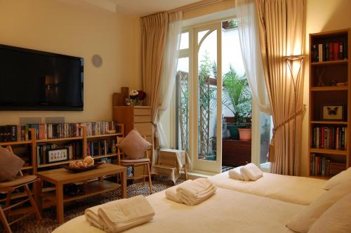 a bedroom with two beds and a tv and a book shelf at Georgiana's Guesthouse in London