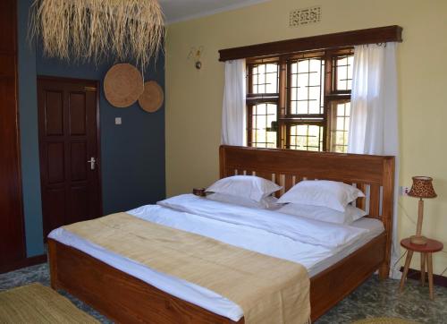 um quarto com uma cama com lençóis brancos e uma janela em Stasumo House Arusha em Arusha