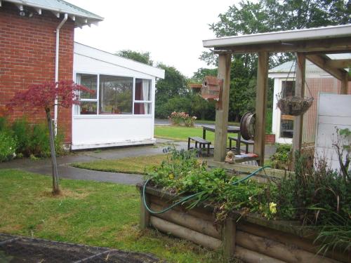 a garden with a shed and a bench in a yard at Thomas's Catlins Lodge and Camp Ground in Owaka