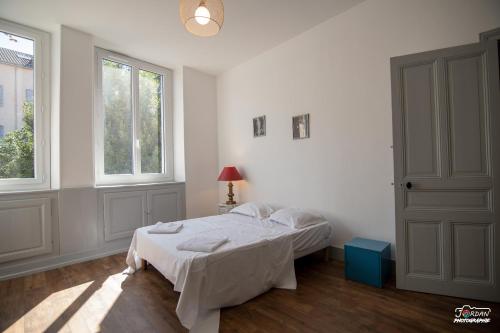 a white bedroom with a bed and two windows at Hyper centre - 3 chambres - Gare - wifi - cosy in Bourg-en-Bresse