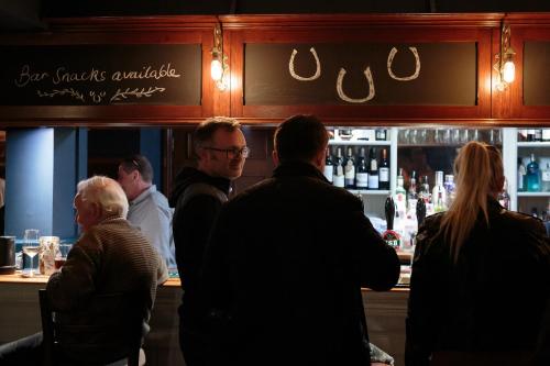 un gruppo di persone in piedi in un bar di The Three Horseshoes East Worldham ad Alton