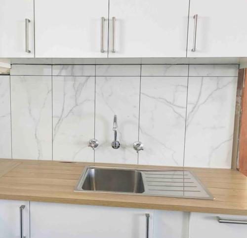 a kitchen counter with a sink and white cabinets at Beachside Unit Brighton in Adelaide