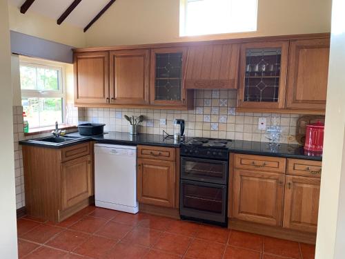 uma cozinha com armários de madeira e bancadas pretas em Brookside Barn em Lichfield