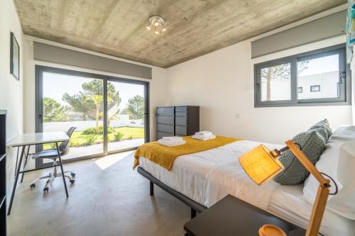 Schlafzimmer mit einem Bett, einem Schreibtisch und einem Fenster in der Unterkunft As Andorinhas - Walking distance to Monte Clerigo and Amoreira beaches in Aljezur