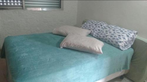 una cama con dos almohadas encima en Apartamento na Praia Grande, en Praia Grande